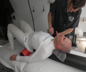 The grey foam roller helps to open Ben Keating’s chest/shoulders while the vibrating red roller relaxes the glutes and Sacro-Iliac area after 90 minutes of intense racing. All the while, Jerry is releasing trigger points along the sternum, collarbones and shoulders. These techniques along with others expedite recovery and aid in preparation for the next driving stint.