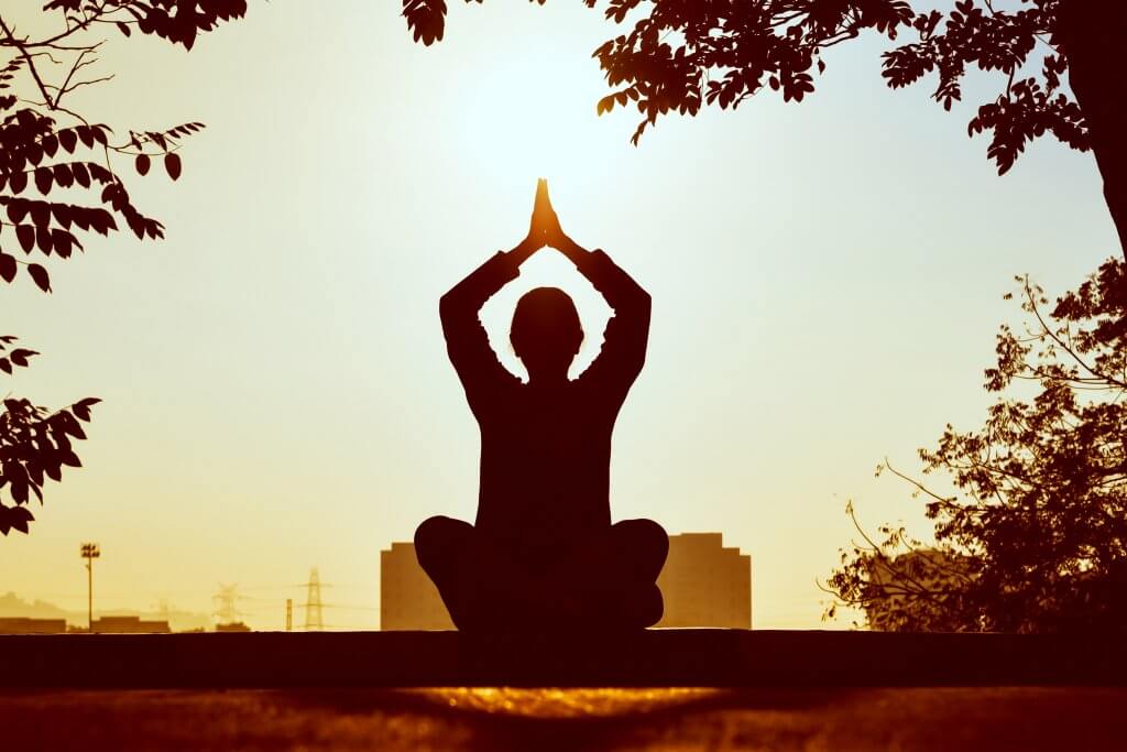 Person meditating in front of skyline