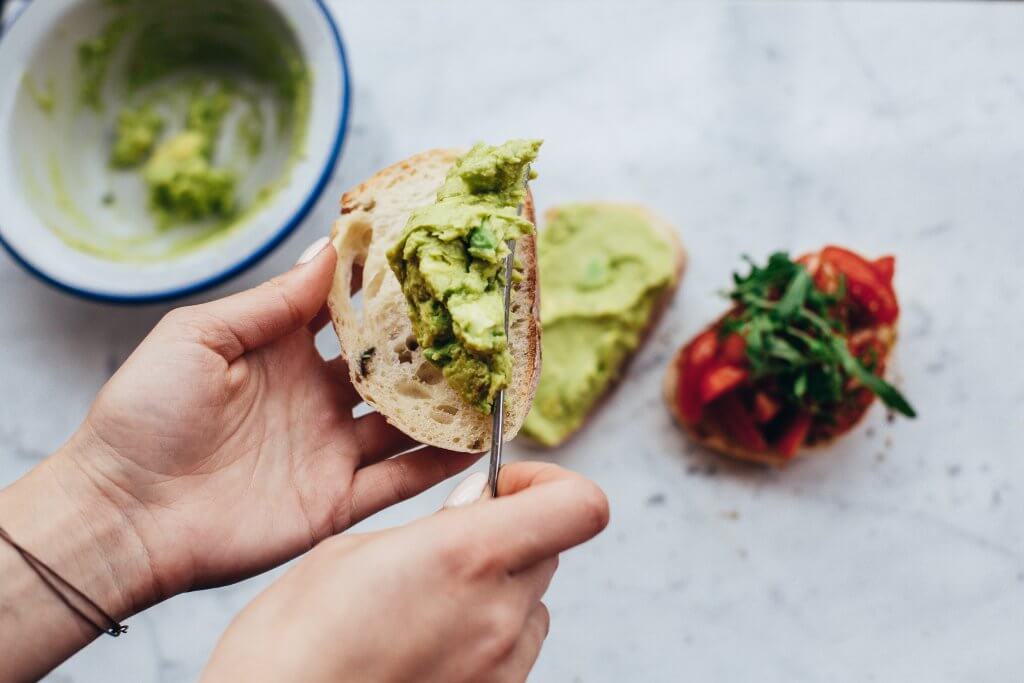 Avocado being spread on bread