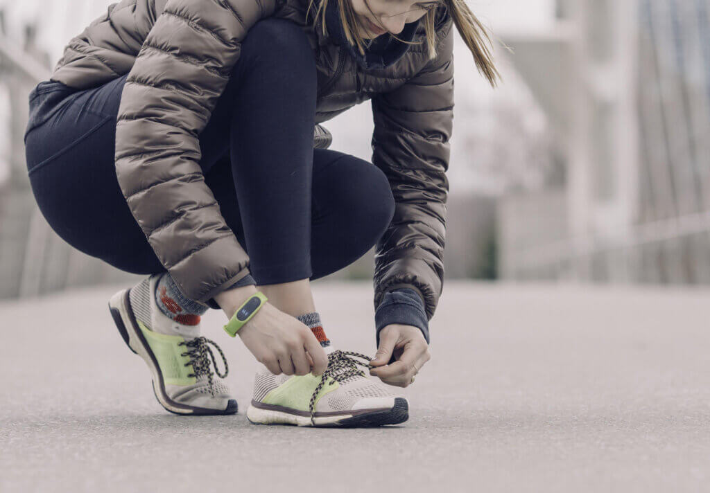 Woman Athlete Tying Shoes in Winter in Health Coach Holiday Survival Guide Blog Banner