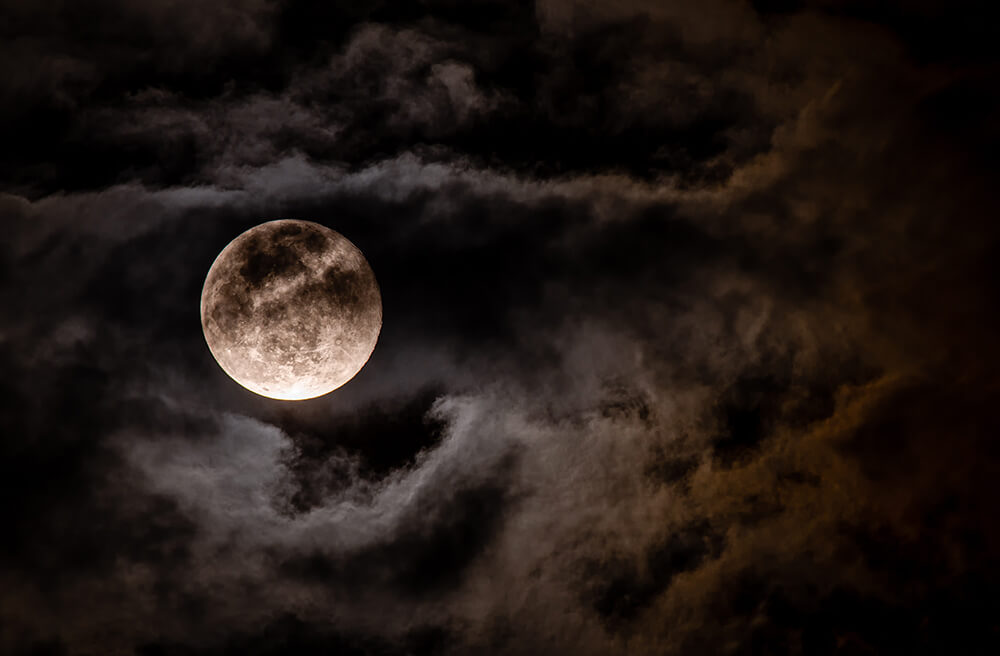 How the Moon Can Guide Your Practice Image of the Full Moon in a cloudy sky