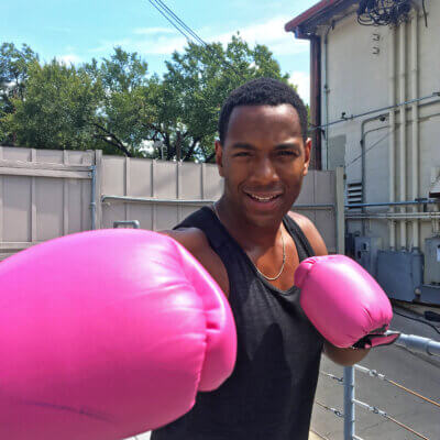 Photo of Fitness Instructor Amid Archibald outside wearing boxing gloves and smiling 