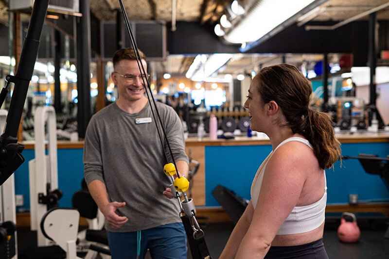 Image of Personal Trainer Clark Honeycutt laughing as he works with a smiling client. 