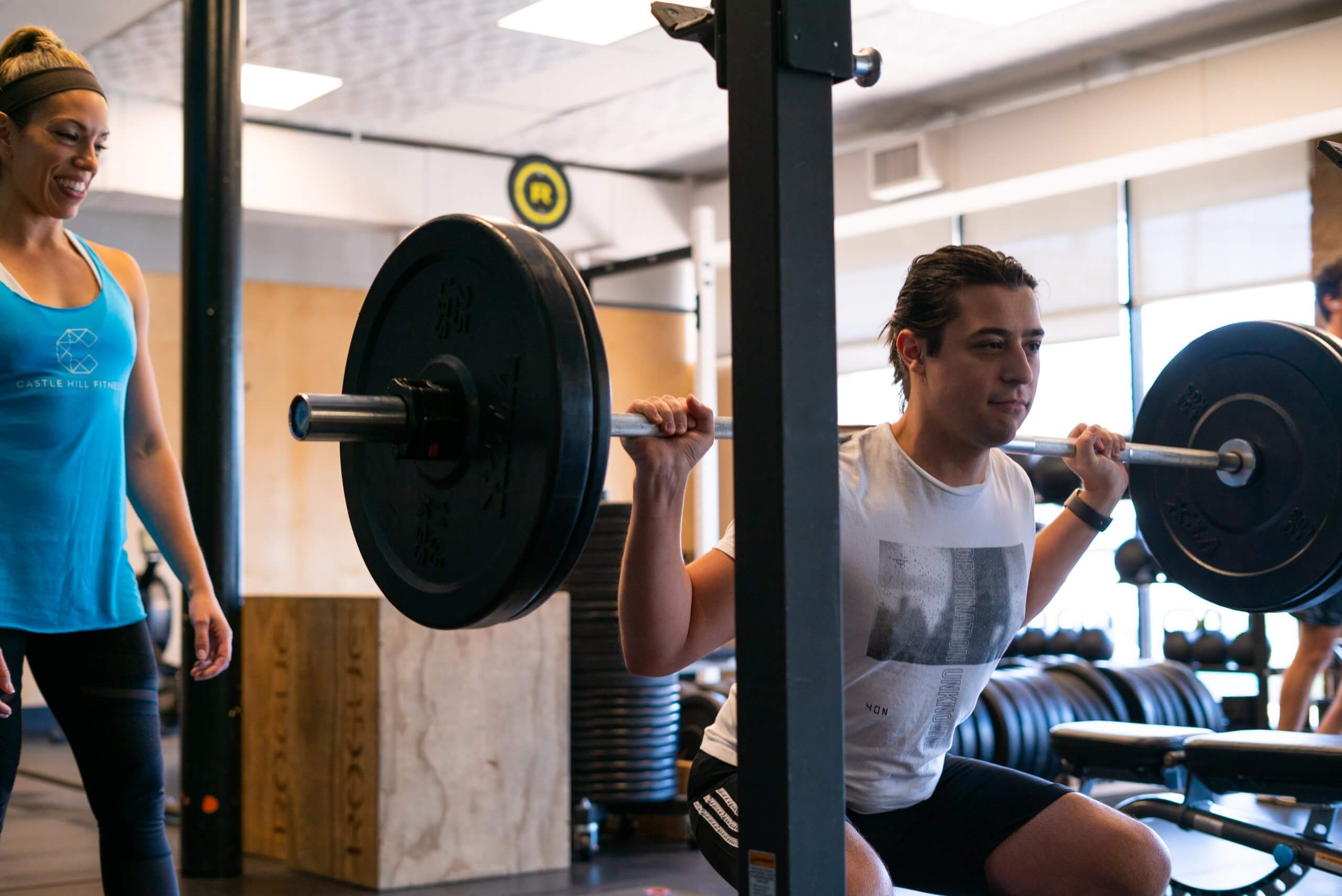Young man performing a barbell squat in the Arena during a personal training session