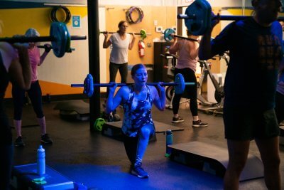 Women in a fitness class weight training with barbells