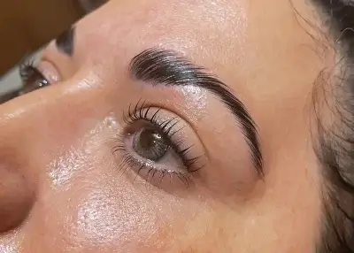 Closeup image of a woman's brows and lashes after a lamination treatment