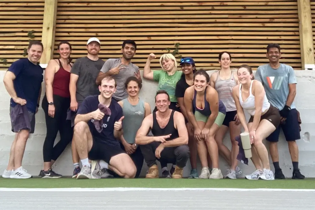 Group of people in an outdoor exercise class posing together and smiling after their workout.