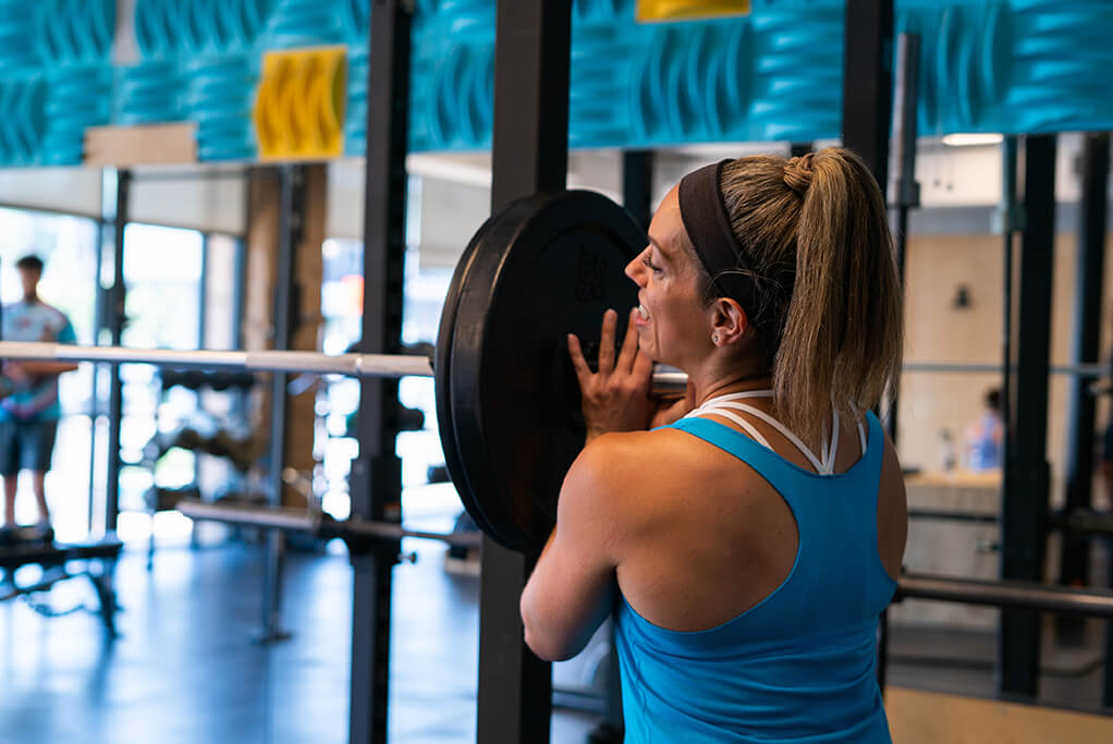 Personal Trainer Sonya Latinovic adding weight plates to a barbell.