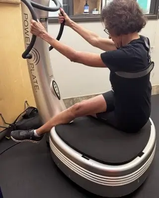 A woman stretching on the Power Plate during a Vibration-Based Proprioceptive Training session at Castle Hill Fitness.