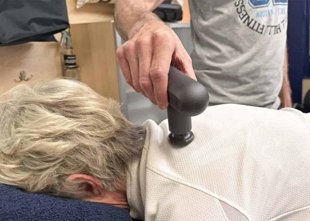 Jerry Gerlich using vibration technology on a woman's back during a Vibration-Based Proprioceptive Training session at Castle Hill Fitness