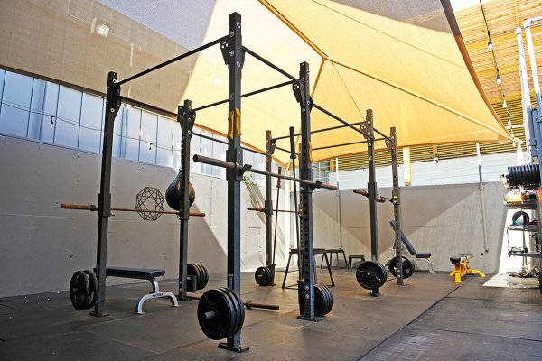 Lower deck of the Outdoor Studio, featuring squat ranks, a bench, and a canvas covering.